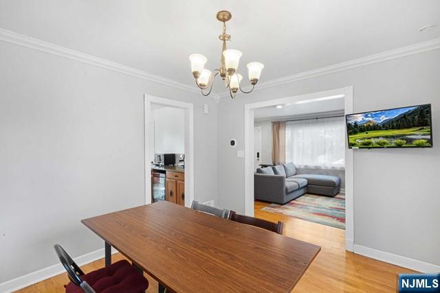 dining space featuring light wood-style flooring, baseboards, and crown molding