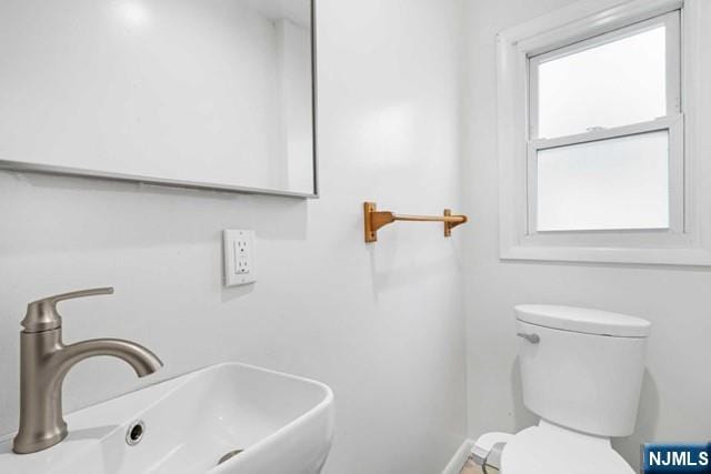 half bathroom featuring baseboards, a sink, and toilet