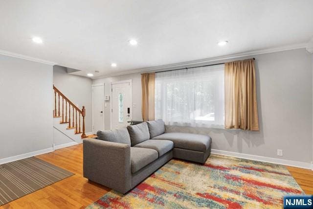 living room featuring ornamental molding, wood finished floors, baseboards, and stairs