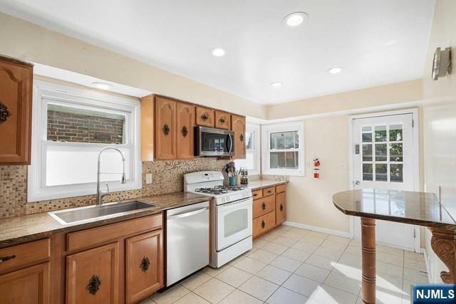 kitchen with appliances with stainless steel finishes, brown cabinetry, a sink, and tasteful backsplash