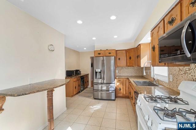 kitchen with appliances with stainless steel finishes, brown cabinets, a sink, and tasteful backsplash