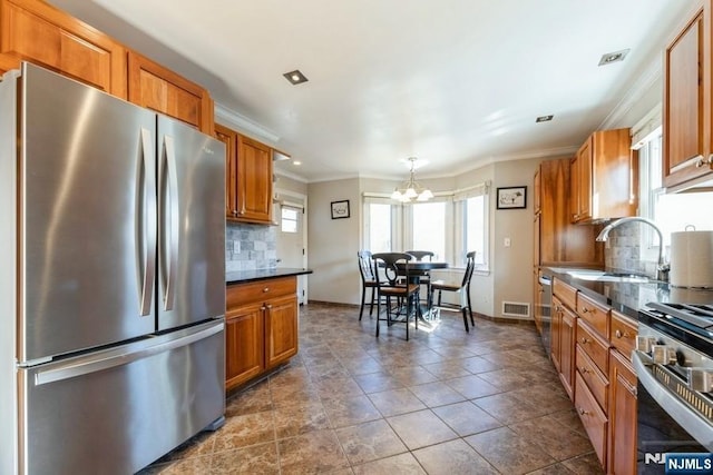 kitchen with visible vents, brown cabinetry, dark countertops, appliances with stainless steel finishes, and a sink