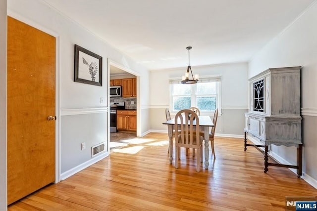 dining space featuring a chandelier, light wood-style flooring, visible vents, and baseboards