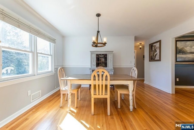 dining area with light wood-type flooring, baseboards, visible vents, and a chandelier