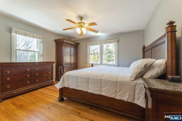 bedroom featuring light wood-style flooring, multiple windows, a ceiling fan, and crown molding