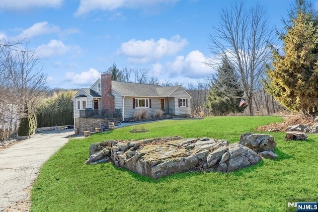 view of front of house with driveway, a chimney, and a front lawn