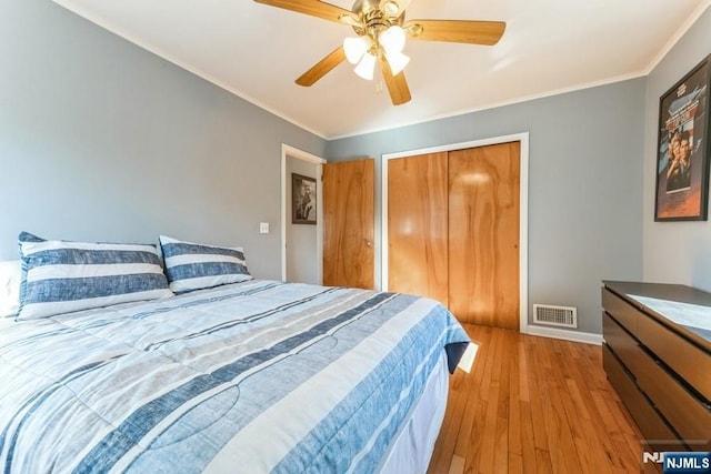 bedroom with ornamental molding, a closet, visible vents, and wood finished floors