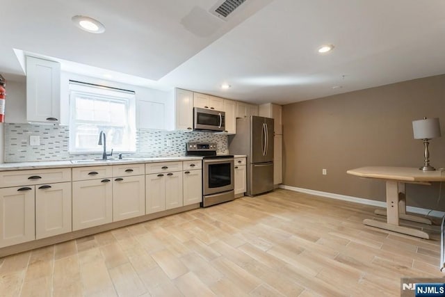 kitchen featuring decorative backsplash, stainless steel appliances, a sink, and light countertops