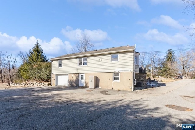 exterior space featuring a garage, driveway, and stucco siding