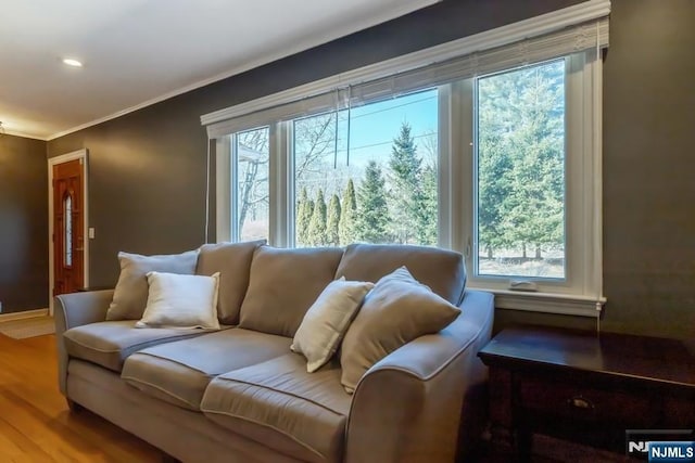 living area featuring recessed lighting, ornamental molding, a wealth of natural light, and wood finished floors