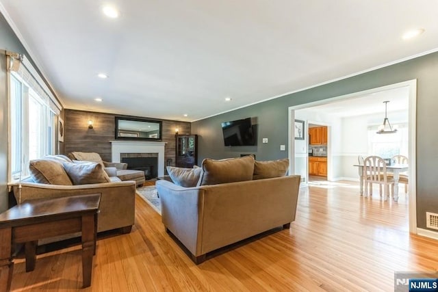 living area featuring ornamental molding, recessed lighting, a fireplace, and light wood-style flooring