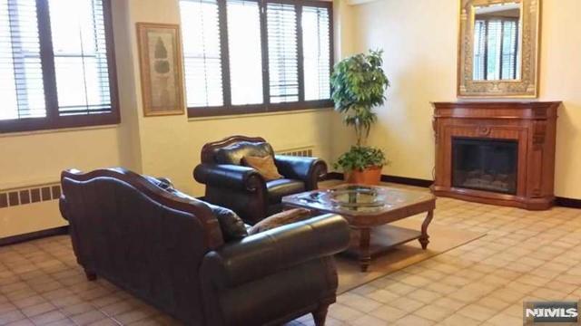 living area featuring radiator and a glass covered fireplace