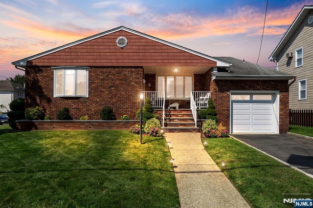 view of front of home featuring brick siding, a front yard, aphalt driveway, and a garage