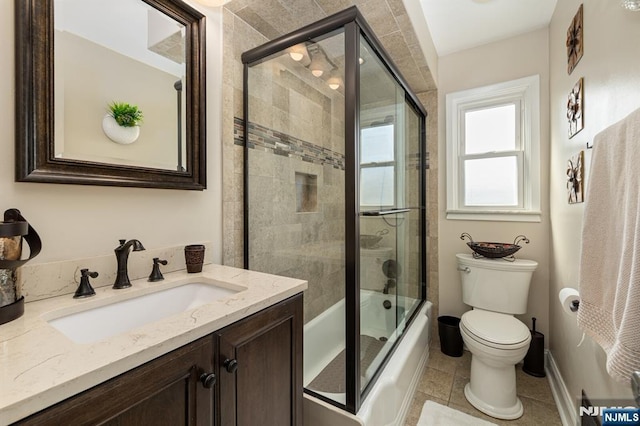 bathroom with baseboards, bath / shower combo with glass door, toilet, tile patterned floors, and vanity