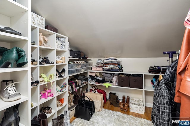 walk in closet with wood finished floors and vaulted ceiling