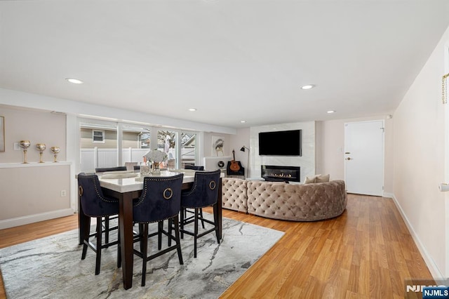 dining room with recessed lighting, light wood-style flooring, a fireplace, and baseboards