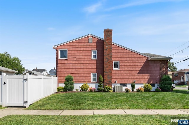 view of home's exterior with a gate, central AC unit, fence, a yard, and a chimney