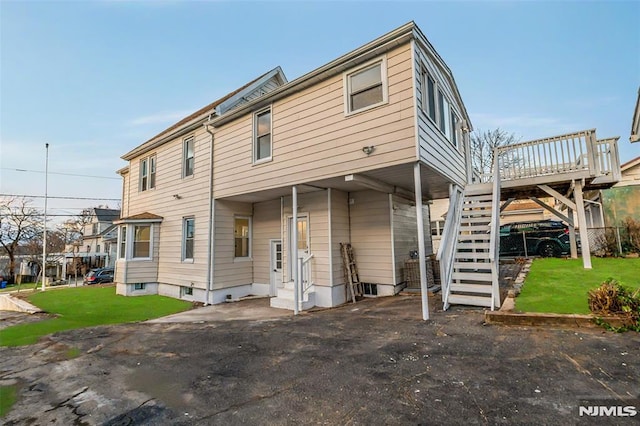 rear view of property featuring entry steps, a lawn, and stairway