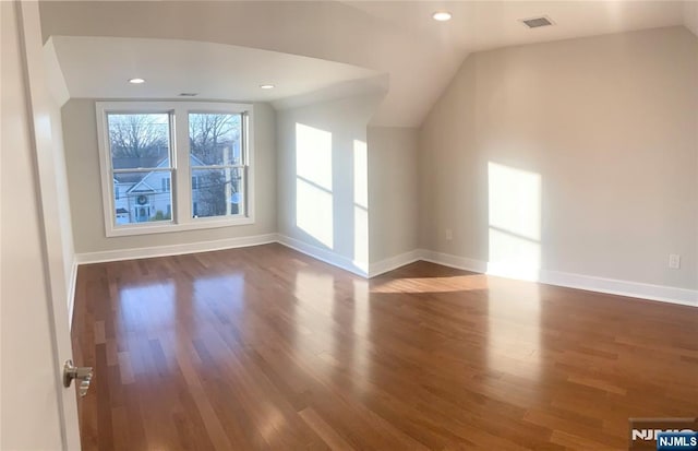 additional living space featuring lofted ceiling, dark wood-type flooring, visible vents, and baseboards