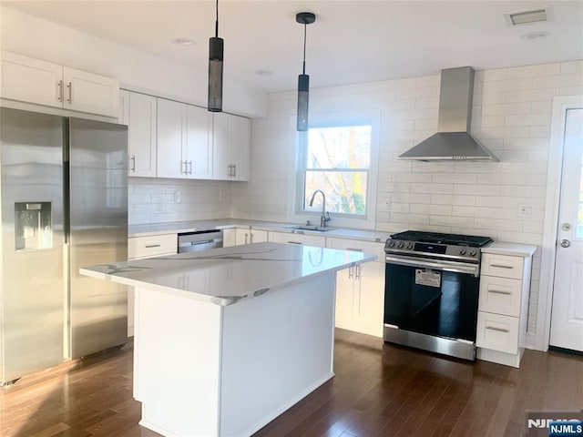 kitchen with stainless steel appliances, dark wood-style flooring, a sink, light countertops, and wall chimney exhaust hood