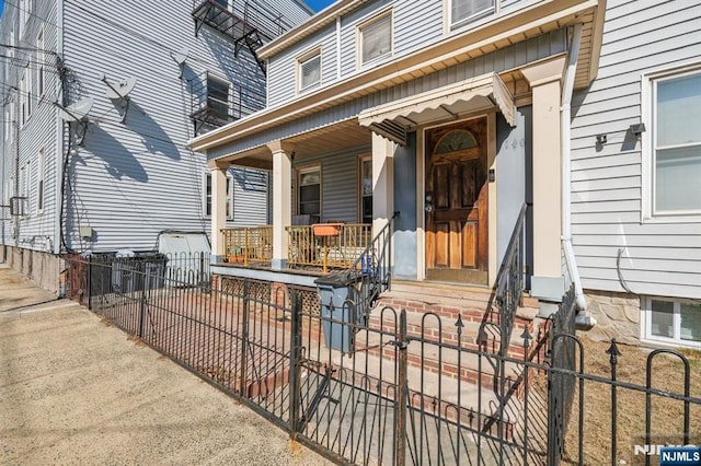 property entrance featuring fence and covered porch