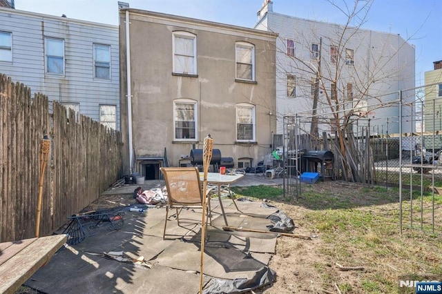 rear view of property with stucco siding, a patio, and a fenced backyard