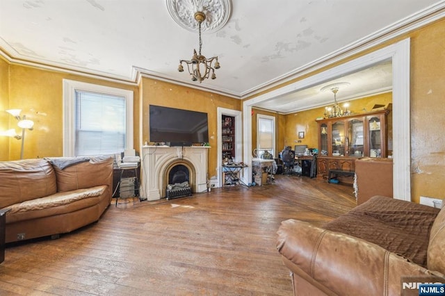 living area with ornamental molding, a fireplace, wood-type flooring, and a chandelier