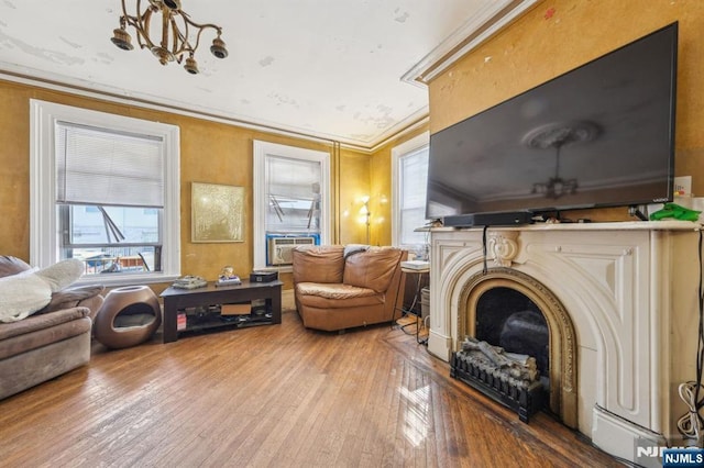 living room with cooling unit, an inviting chandelier, a fireplace, ornamental molding, and wood-type flooring