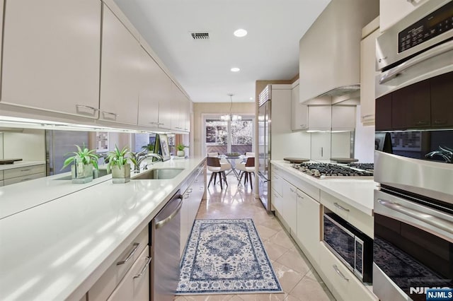 kitchen featuring light countertops, custom range hood, visible vents, appliances with stainless steel finishes, and a sink