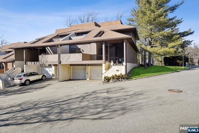 view of front of home featuring a garage, roof with shingles, and a balcony