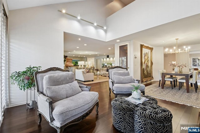 living room featuring recessed lighting, a notable chandelier, dark wood-style flooring, a towering ceiling, and baseboards