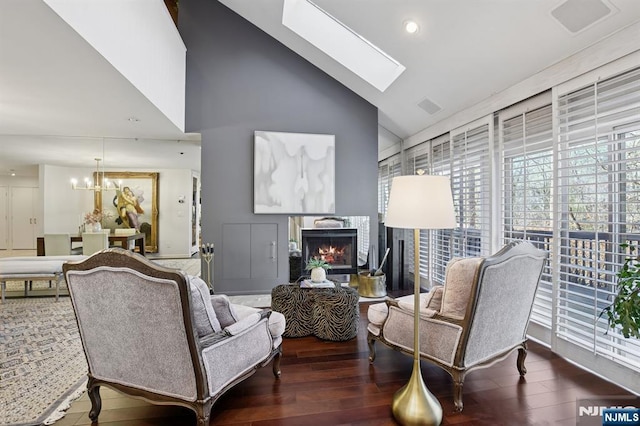 living room featuring a warm lit fireplace, wood finished floors, plenty of natural light, and a skylight