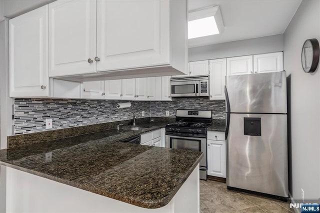 kitchen with decorative backsplash, appliances with stainless steel finishes, and white cabinetry