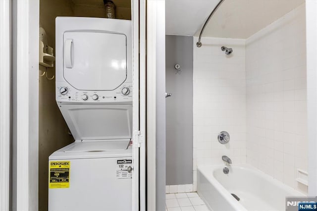 full bathroom with tile patterned flooring, stacked washer and dryer, washtub / shower combination, and baseboards