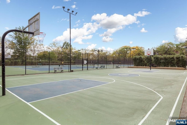 view of sport court featuring a tennis court, community basketball court, and fence