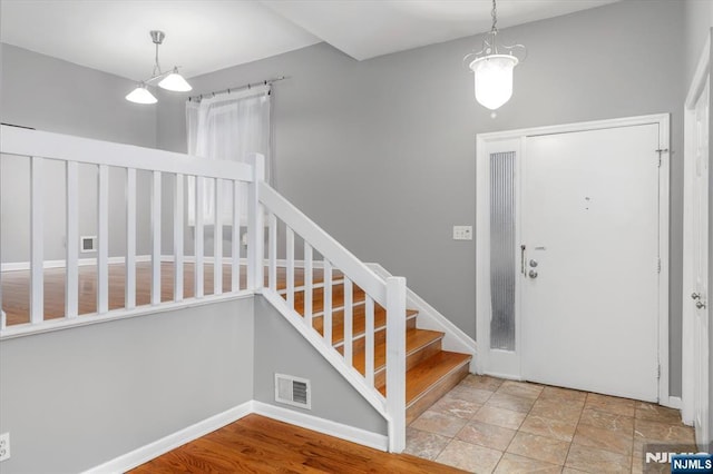 foyer entrance with visible vents, stairs, and baseboards