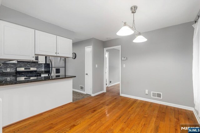 kitchen with baseboards, visible vents, light wood finished floors, stainless steel appliances, and white cabinets