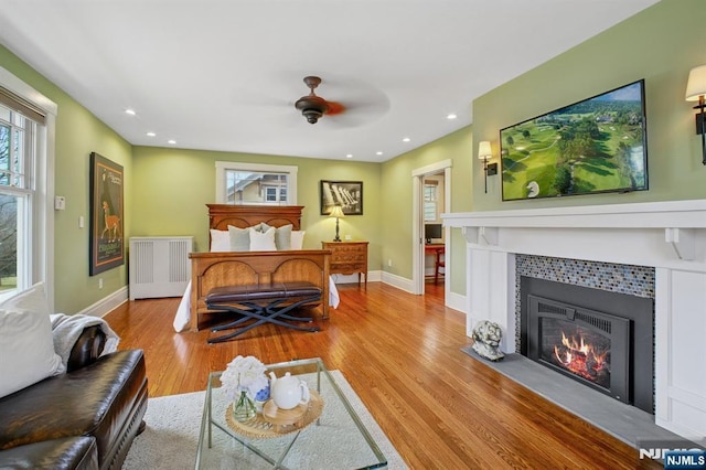 living room featuring a tile fireplace, a healthy amount of sunlight, radiator heating unit, and wood finished floors