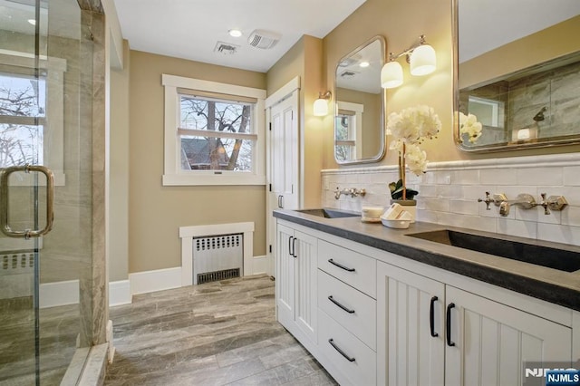 bathroom with a stall shower, radiator, and a sink