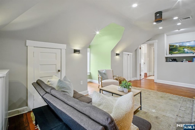 living area with lofted ceiling, baseboards, visible vents, and wood finished floors