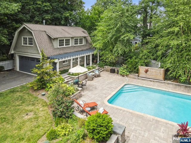 pool with an outbuilding, a patio, and fence