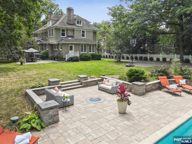 view of patio with fence and an outdoor living space with a fire pit