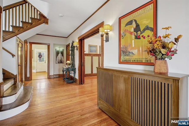 hallway with baseboards, stairway, wood finished floors, and crown molding