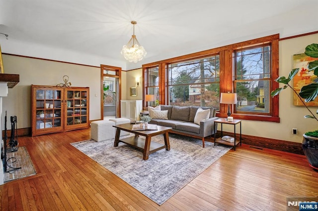 living area with an inviting chandelier, wood-type flooring, visible vents, and baseboards