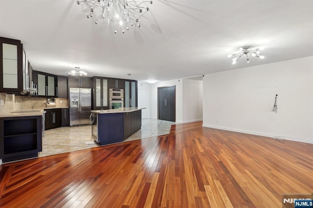 unfurnished living room featuring light wood-style floors, baseboards, and a notable chandelier