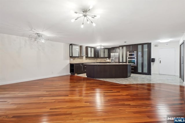 kitchen featuring a center island, a notable chandelier, stainless steel appliances, tasteful backsplash, and light wood-style floors