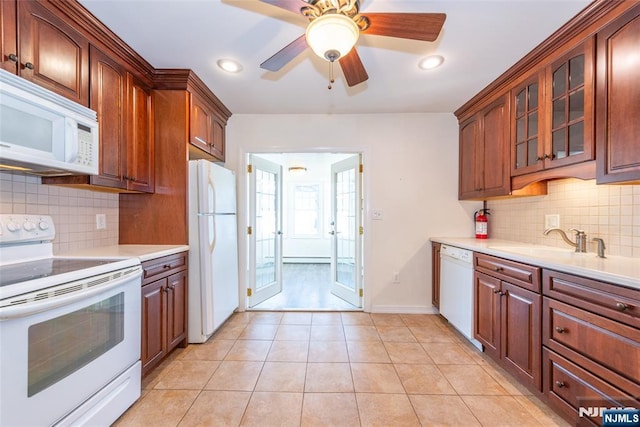 kitchen with white appliances, light tile patterned floors, a sink, light countertops, and glass insert cabinets