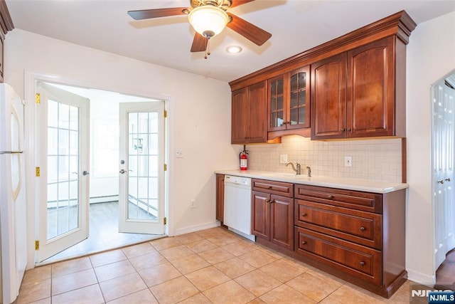 kitchen with white appliances, a sink, light countertops, glass insert cabinets, and backsplash