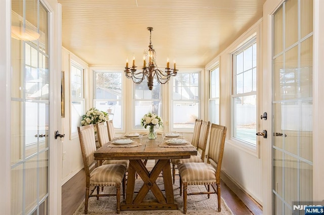 sunroom / solarium featuring a wealth of natural light, french doors, and a chandelier