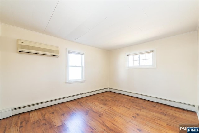 spare room with a wealth of natural light, a baseboard heating unit, wood finished floors, and a wall unit AC